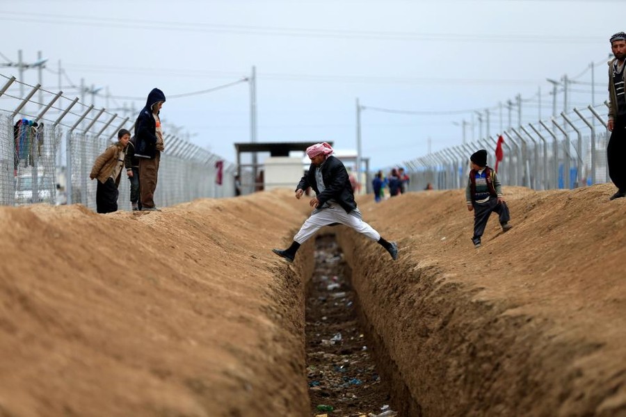 Một người  dân thường Iraq chạy các cuộc giao tranh ở Mosul đang nhảy qua rãnh mương tại trại Khazer. Ảnh Reuters